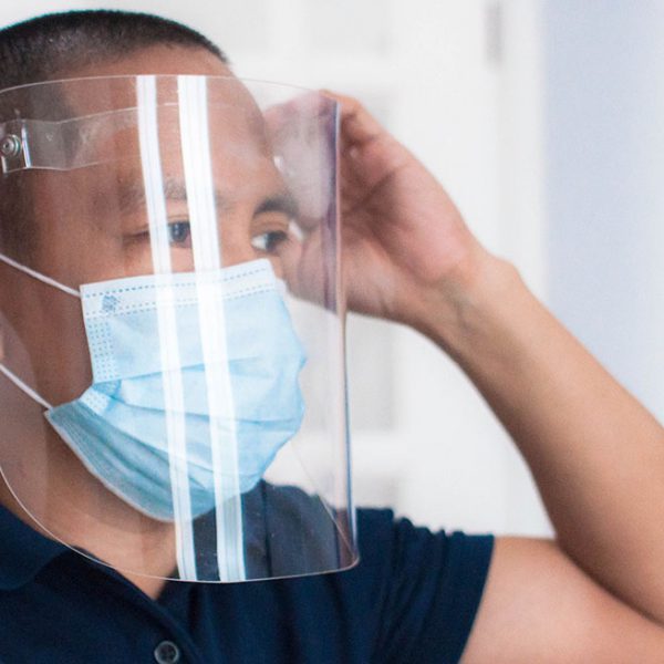 Photograph of a man wearing protective face mask and face shield in the office